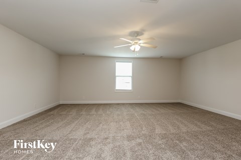 a spacious living room with carpet and a ceiling fan