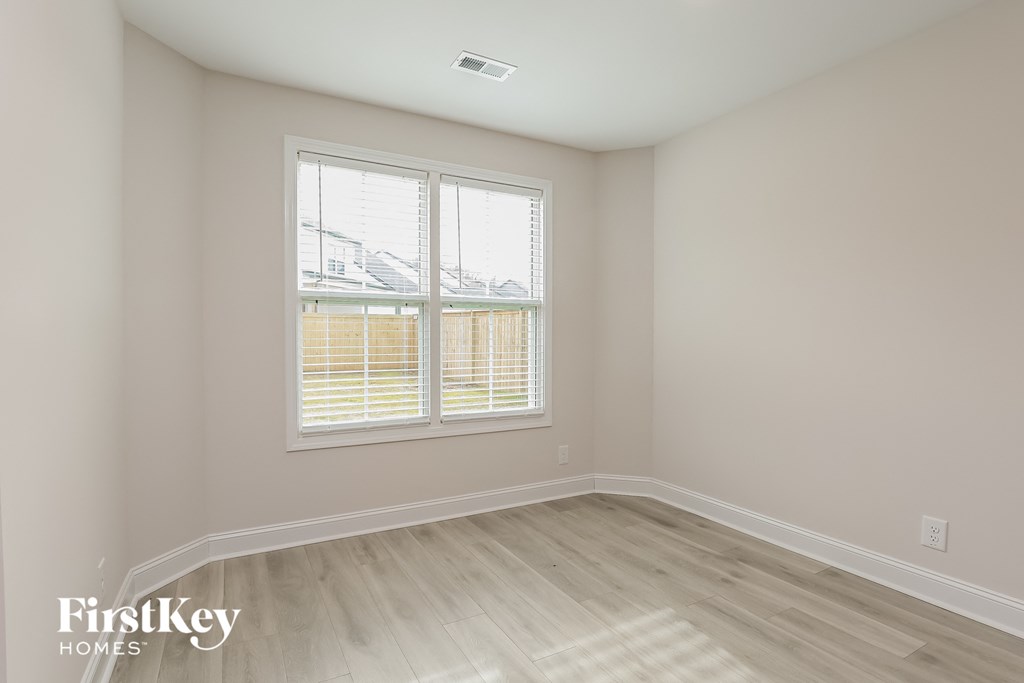 a bedroom with a window and wooden floors