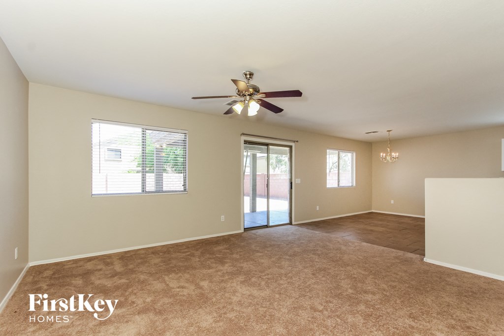 an empty living room with a ceiling fan and a door to a patio