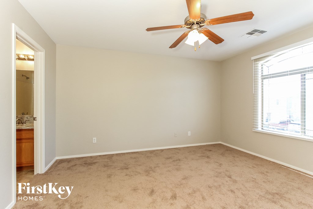 a living room with a ceiling fan and a carpet