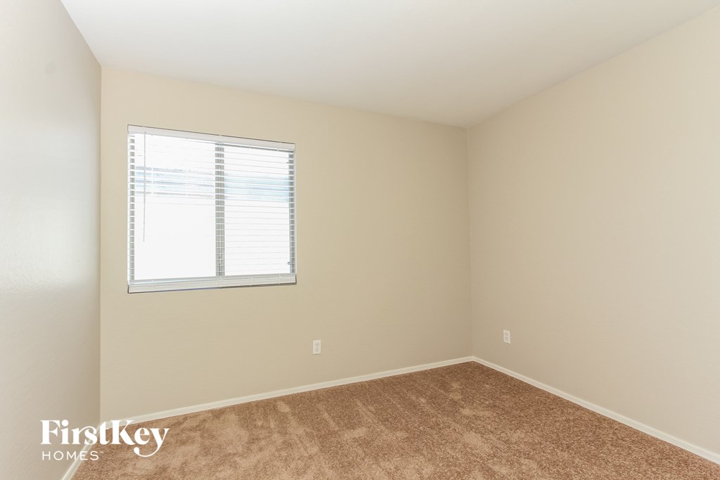 a bedroom with a window and a carpeted floor