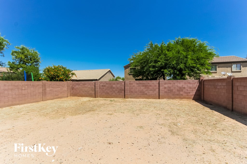 a backyard with a retaining wall and a house in the background