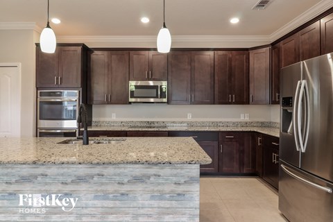 A modern kitchen with a granite countertop and stainless steel appliances.