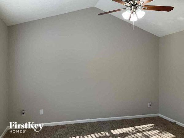 a empty room with a ceiling fan and a white wall