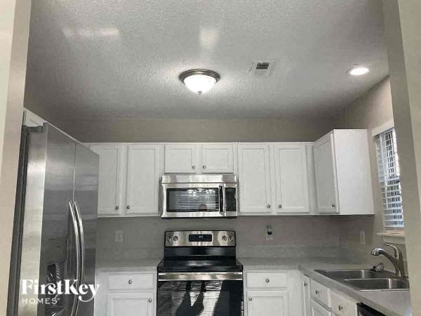 a kitchen with white cabinets and a stove and a microwave