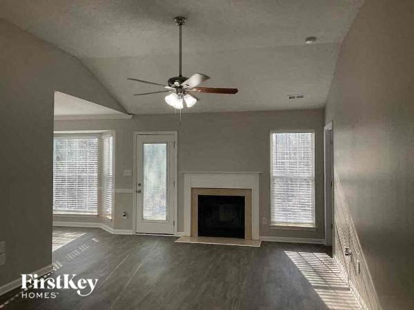 a empty living room with a ceiling fan and a fireplace