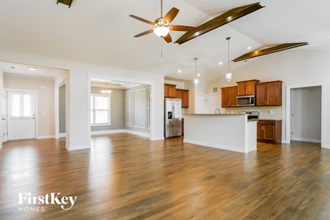 A spacious kitchen and living room with wooden floors and a ceiling fan.