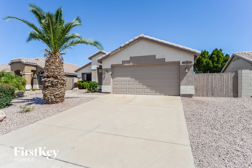 A palm tree stands in front of a house with a garage.