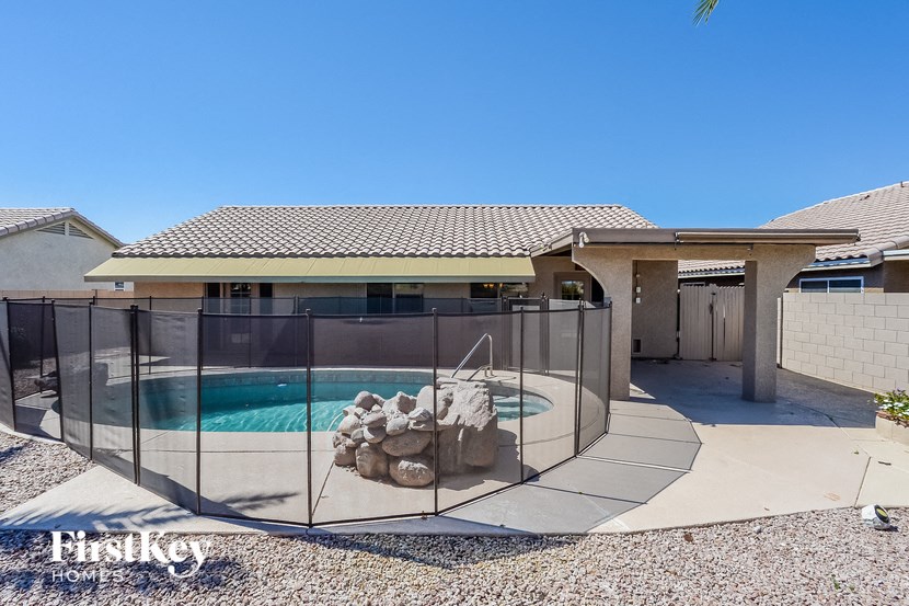 A house with a pool and a fence surrounding it.