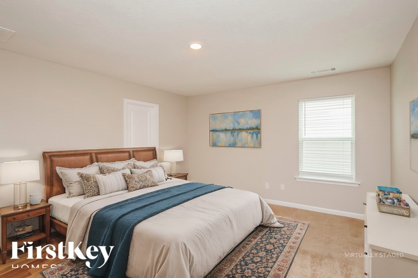 A bedroom with a large bed and a painting on the wall.