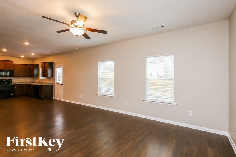A spacious room with wooden floors and a ceiling fan.