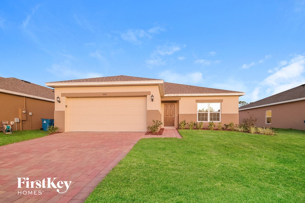 a beige house with a lawn and a garage door