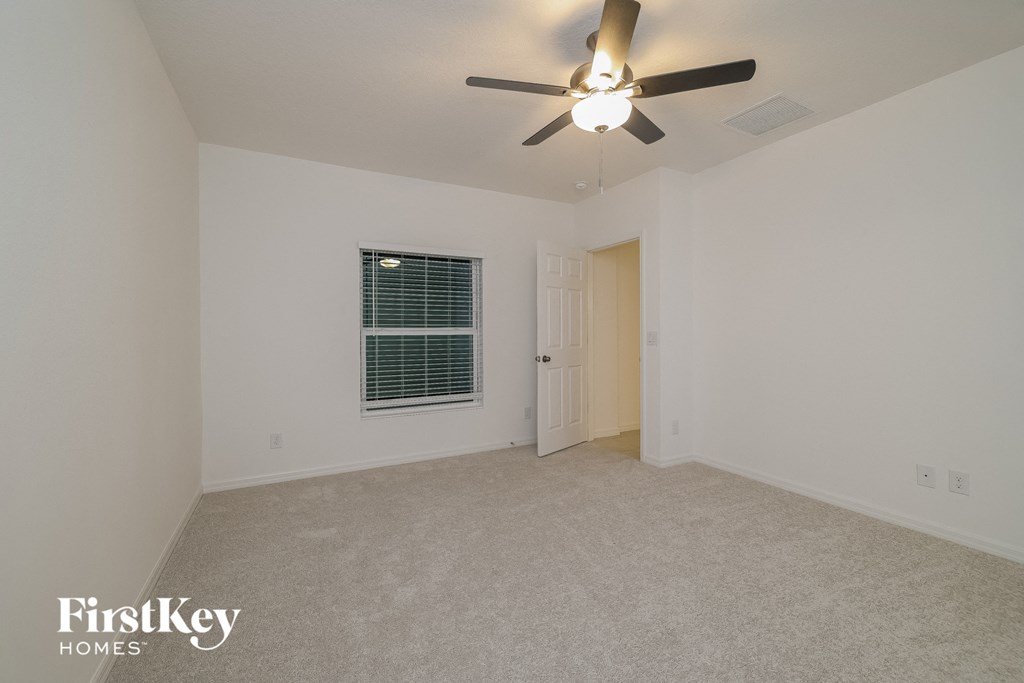 a bedroom with white walls and a ceiling fan