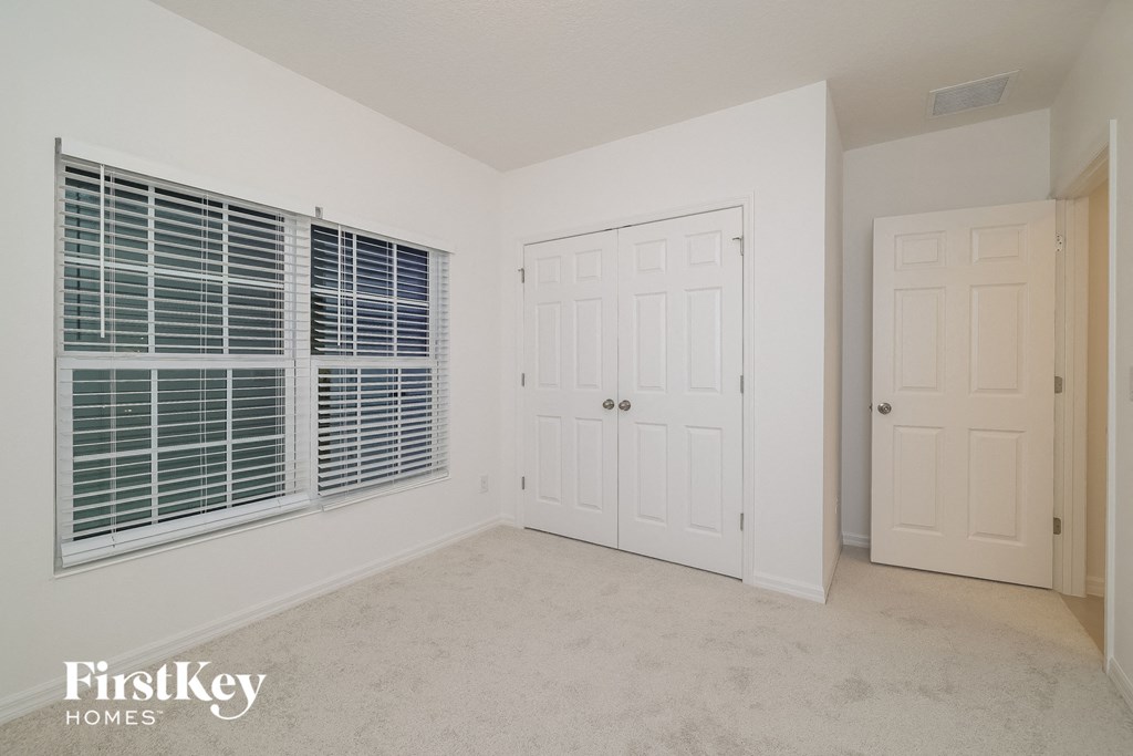 a bedroom with a large window and a white door and a closet