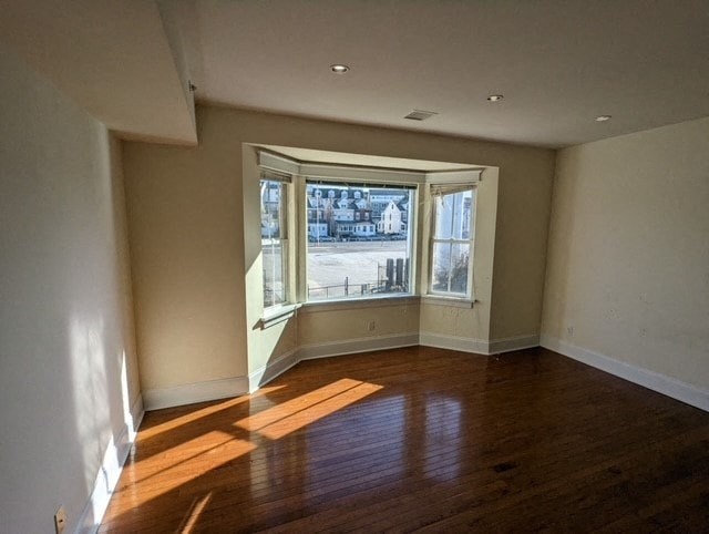 an empty living room with a large window and wooden floors