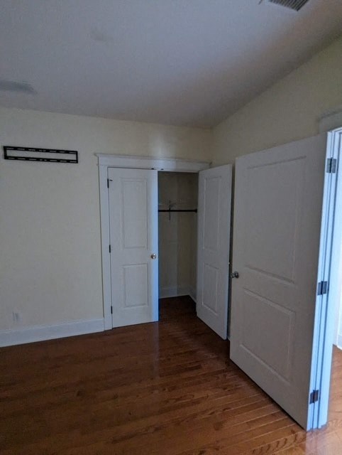 an empty room with white doors and a wood floor
