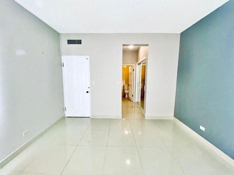 an empty living room with a white tile floor and blue walls