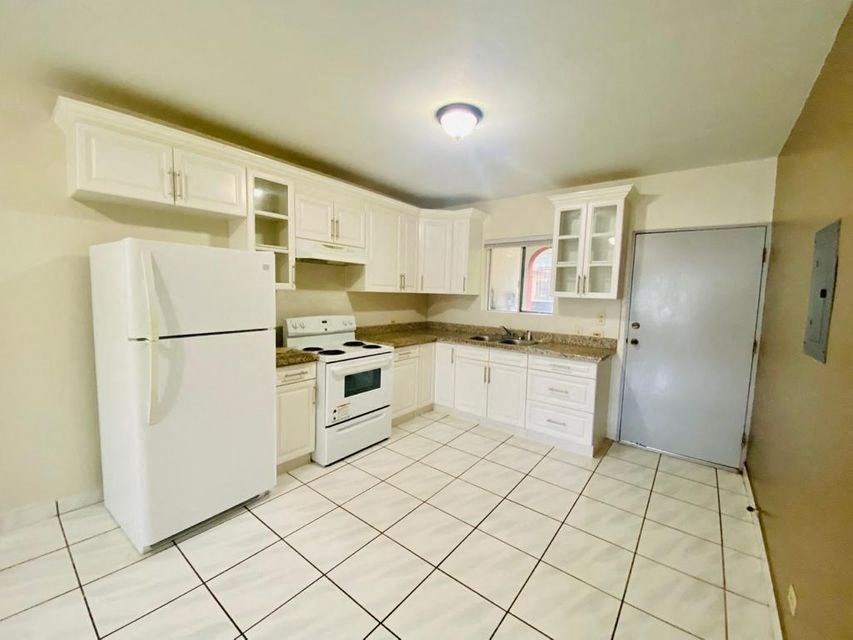 a white kitchen with a refrigerator and a sink