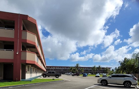 a parking lot in front of a hotel with cars parked