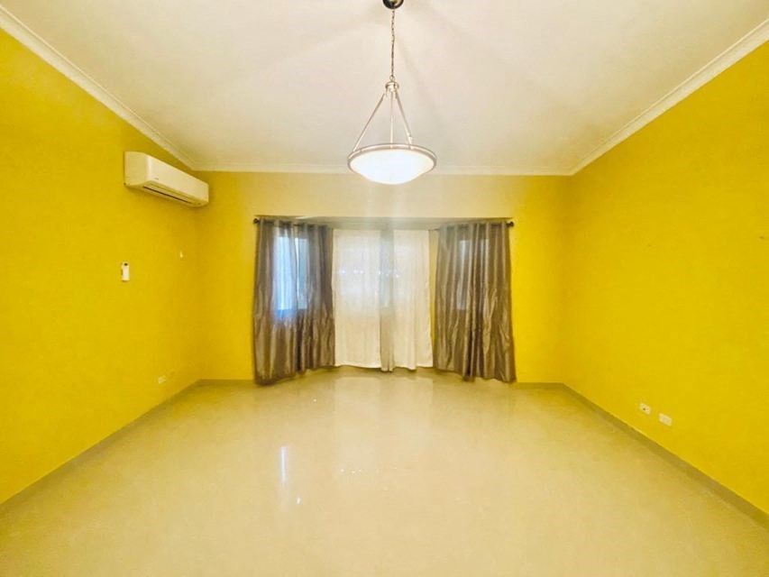an empty living room with yellow walls and a ceiling light
