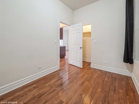 a living room with a door open to a hallway with wood floors