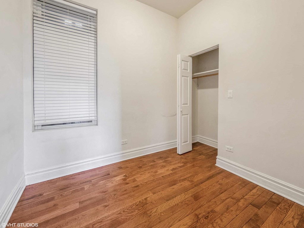 a bedroom with a closet and a window and wood floors
