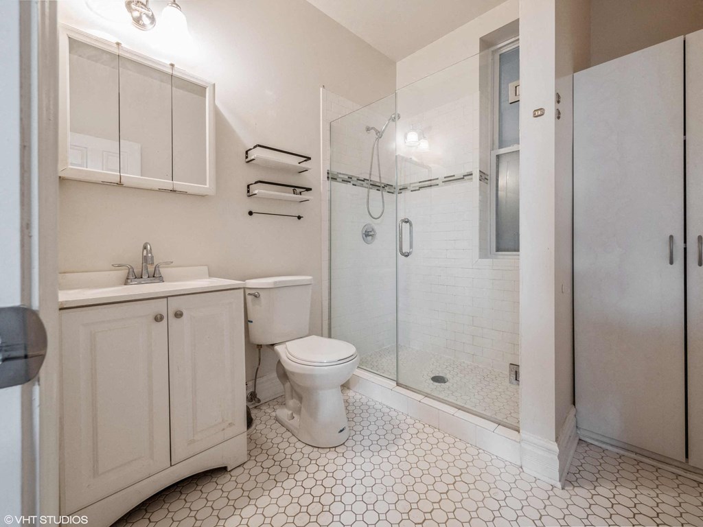 a white bathroom with a shower toilet and sink