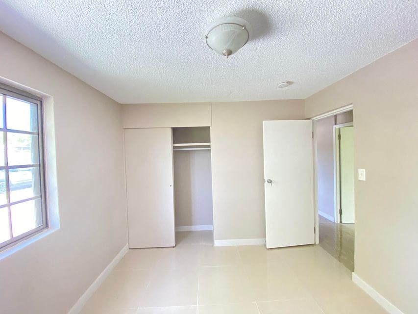 an empty living room with a large window and a mirrored closet