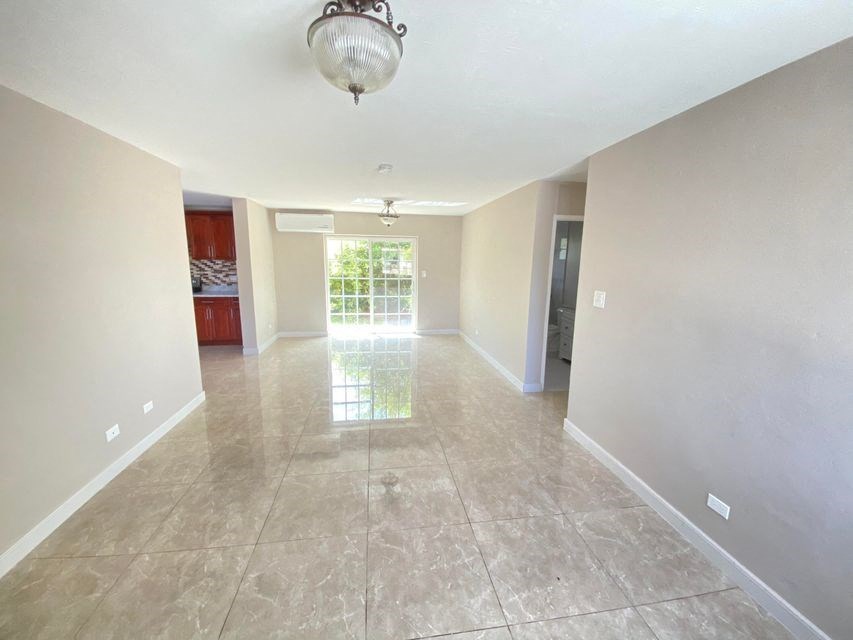 a large empty living room with tile flooring and a window