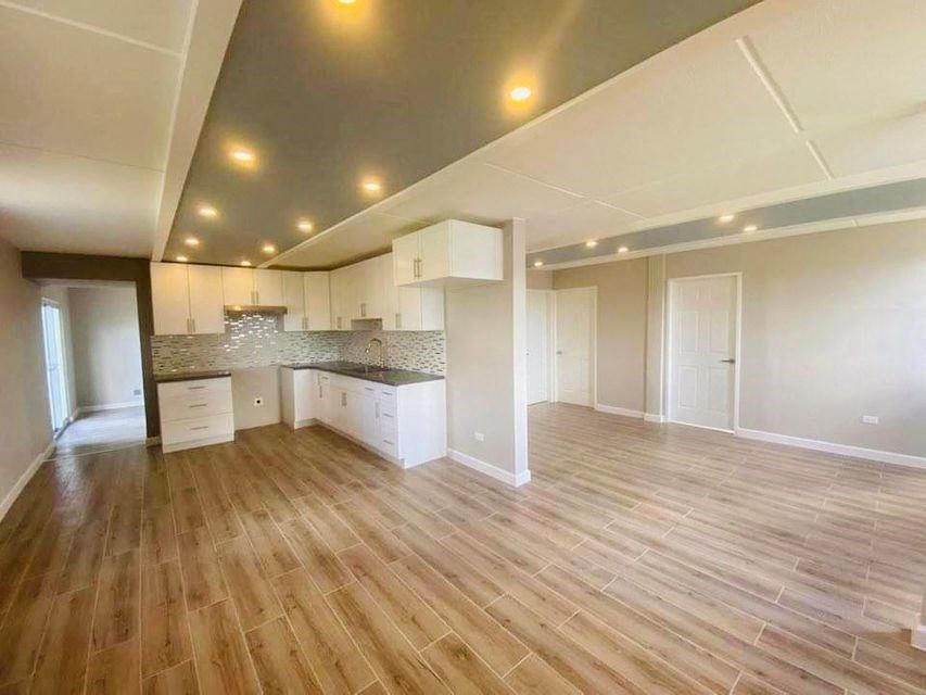 an empty living room and kitchen with a wooden floor