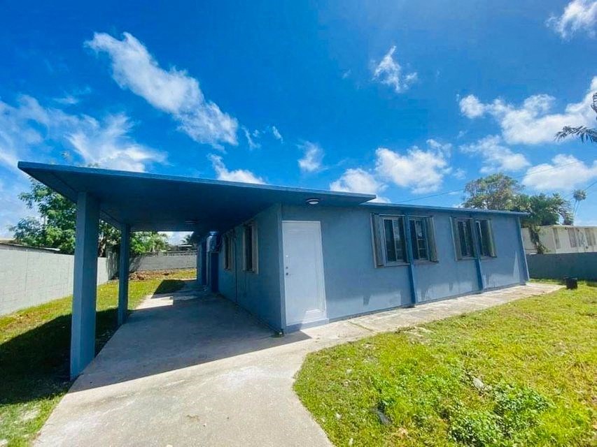 a small blue house with a covered porch on a sunny day