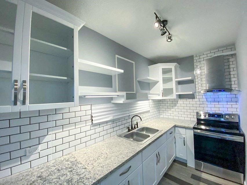 a kitchen with white cabinets and a sink and a stove