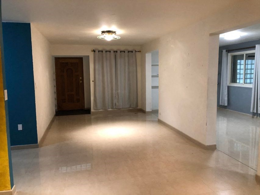 an empty living room with white walls and a tile floor