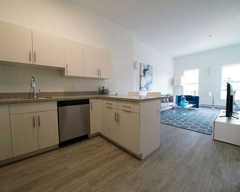 A kitchen with white cabinets and a wooden floor.