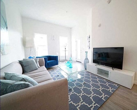 A living room with a couch, a television, and a glass coffee table.