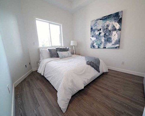 A bedroom with a large bed and a painting on the wall.