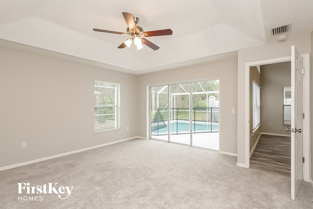 a living room with a ceiling fan and a door to a pool