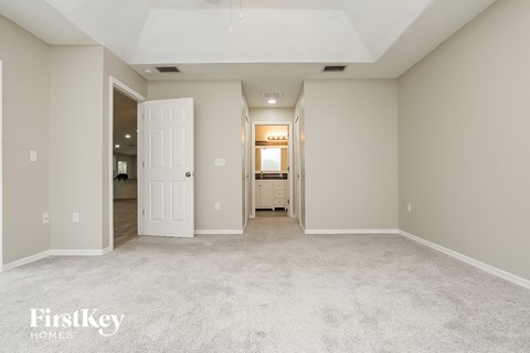 a spacious living room with white carpet and a white door to the bathroom