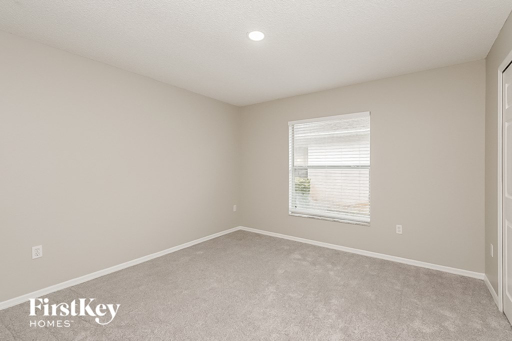 a bedroom with white carpet and a window