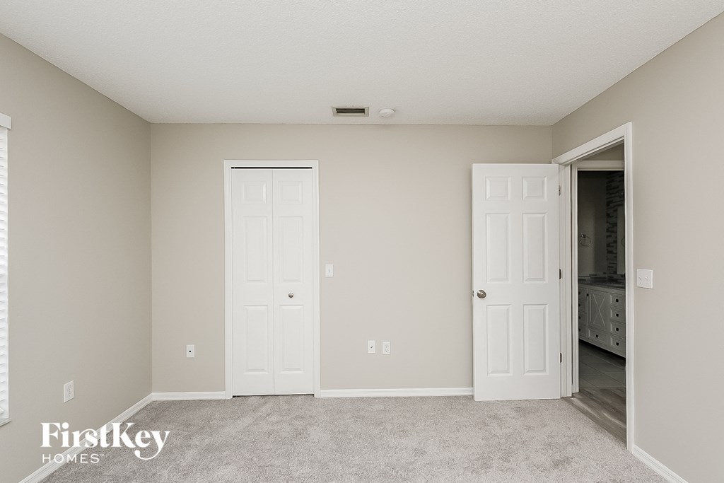 a bedroom with two white doors and a closet