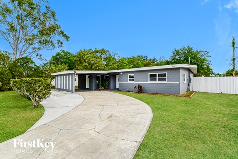 a blue house with a driveway and a white fence
