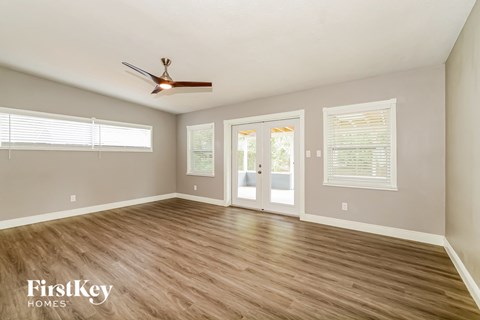 an empty living room with wood floors and a ceiling fan
