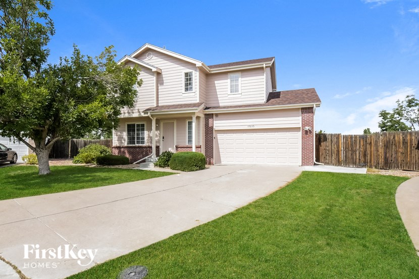 a white and brick house with a driveway and lawn