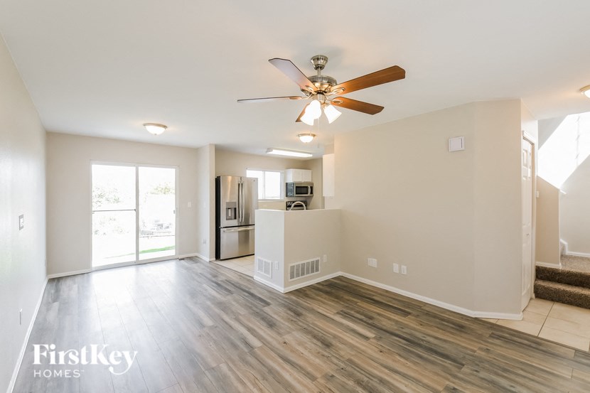 an empty living room with a ceiling fan and a kitchen