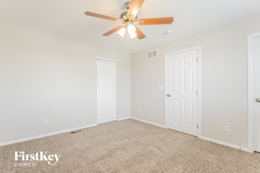 a bedroom with white walls and a ceiling fan