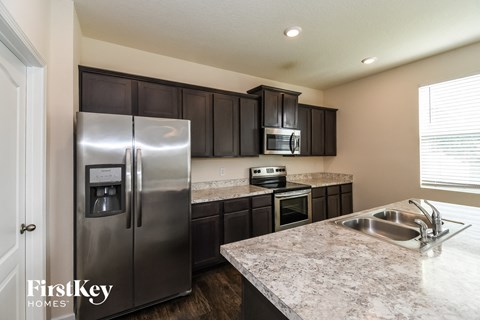 A kitchen with a stainless steel refrigerator and dark brown cabinets.