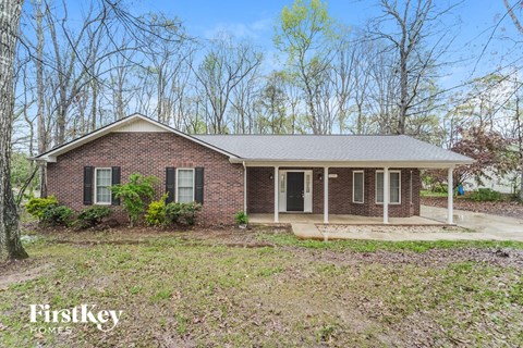 a small brick house with trees in the background