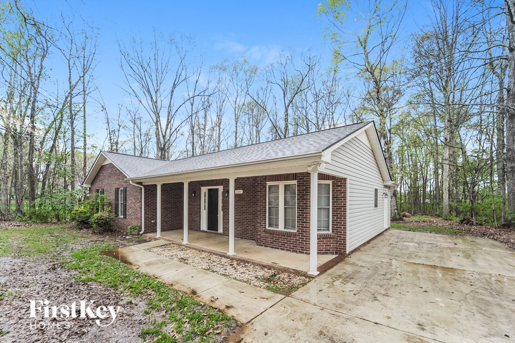 a small brick house with a porch and a driveway