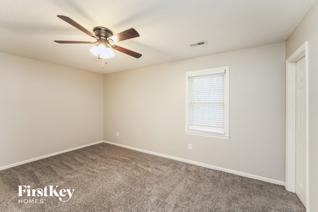 an empty room with a ceiling fan and a window