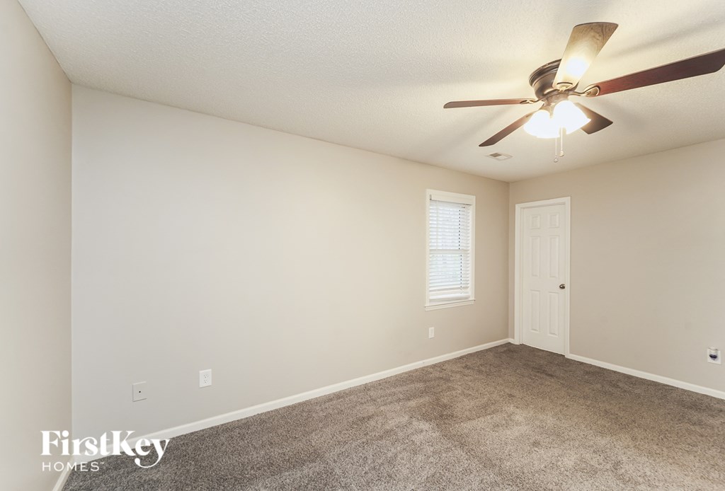 the spacious living room with carpet and a ceiling fan